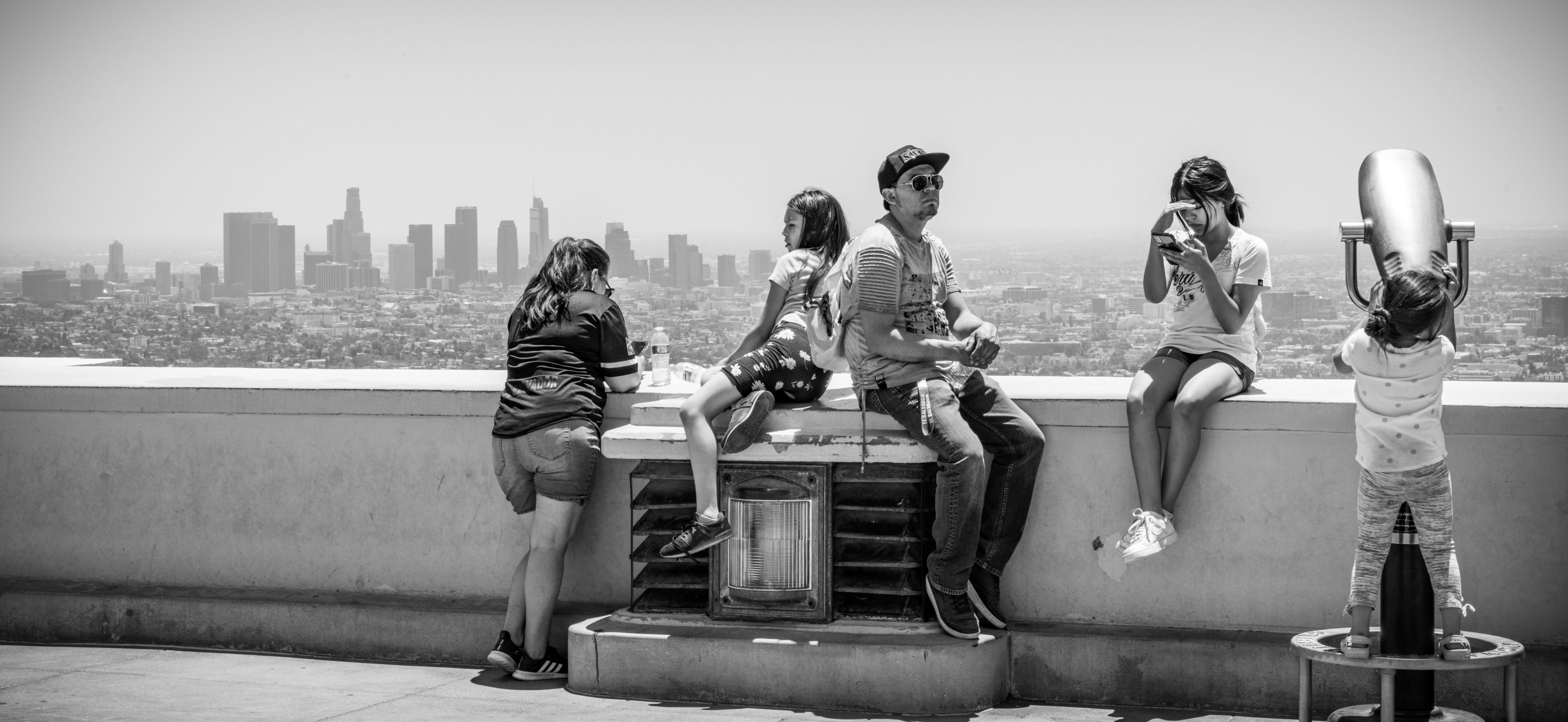 A group of five people enjoy a panoramic view of a city skyline from a high vantage point.